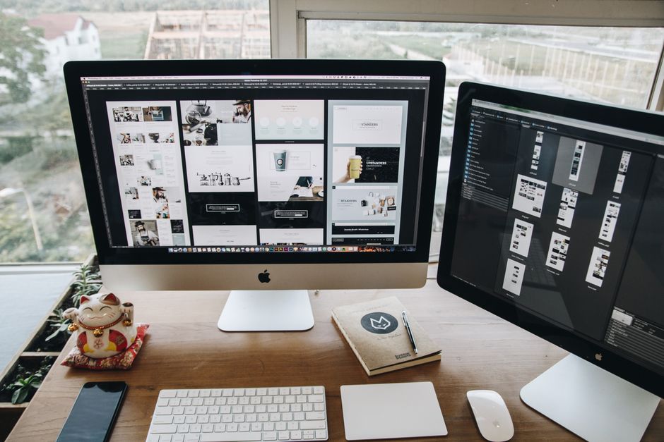 Dobro organizirani radni prostor s dvama Apple iMac računalima na drvenom stolu